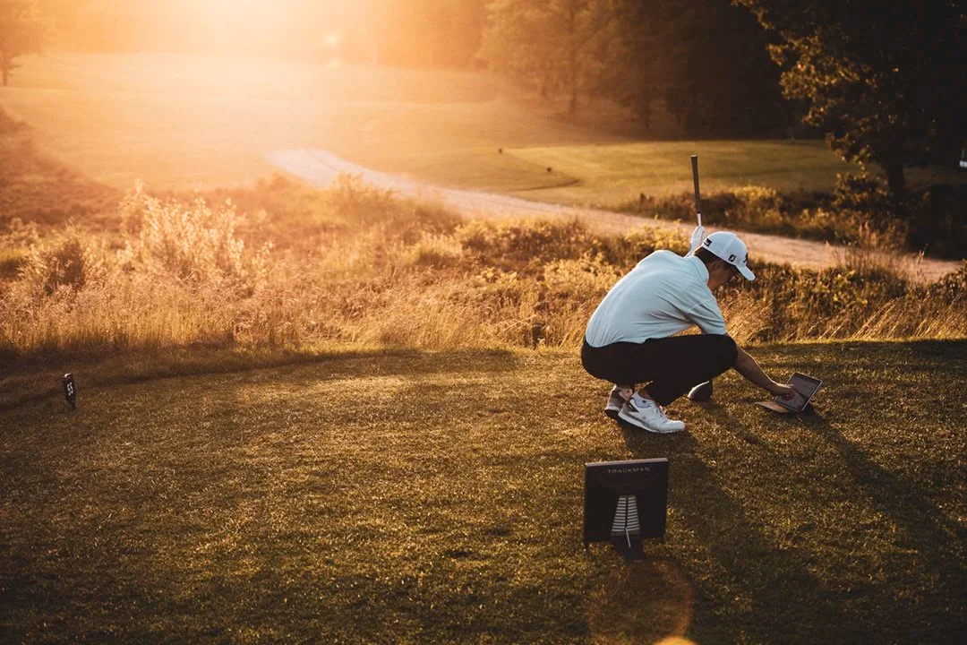 Un golfeur consulte une tablette posée à côté d’un radar sur une aire de départ.