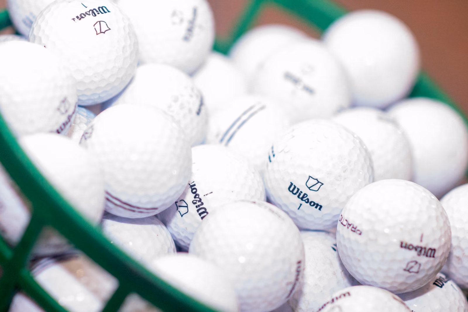 Les alvéoles des balles de golf, serrées dans un panier de practice vert.