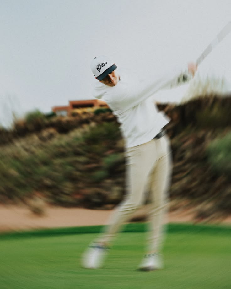 Un golfeur en polo blanc dans le filé de son swing